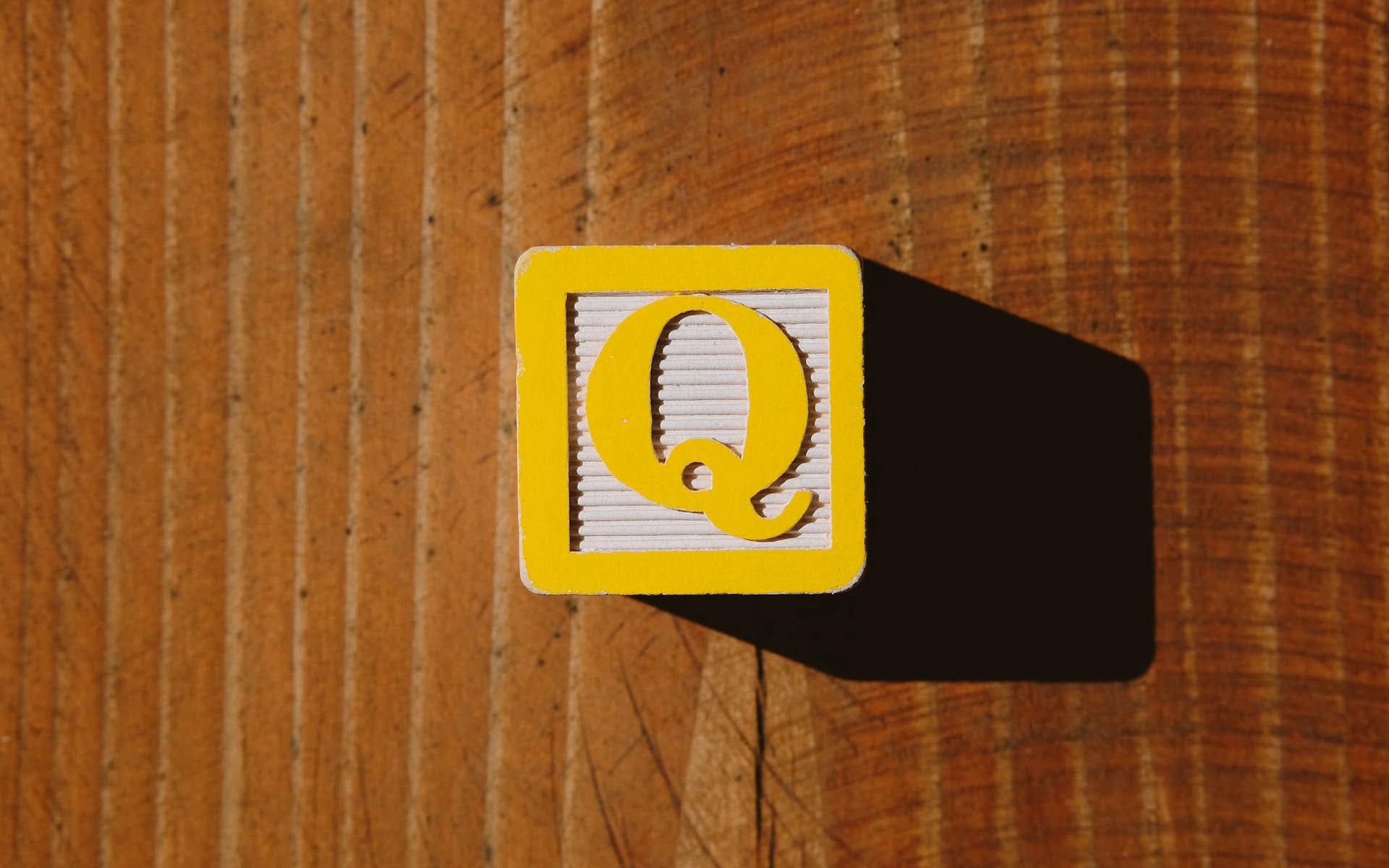 Gelber Würfel mit dem Buchstaben Q