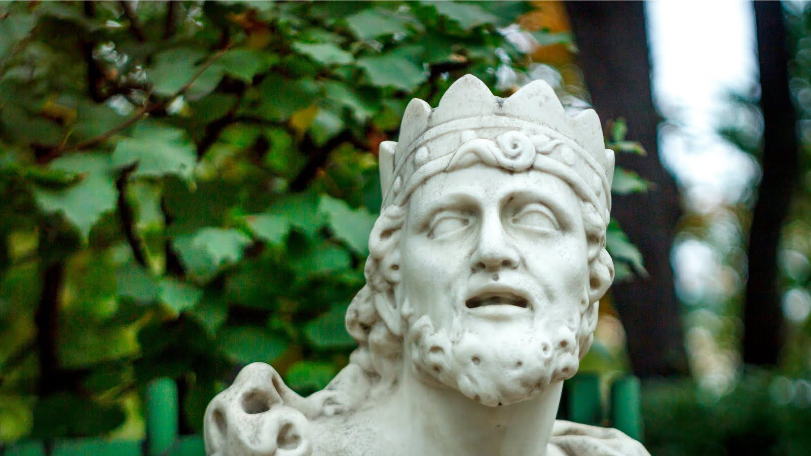 Gekrönte Marmorstatue vor Laubwerk